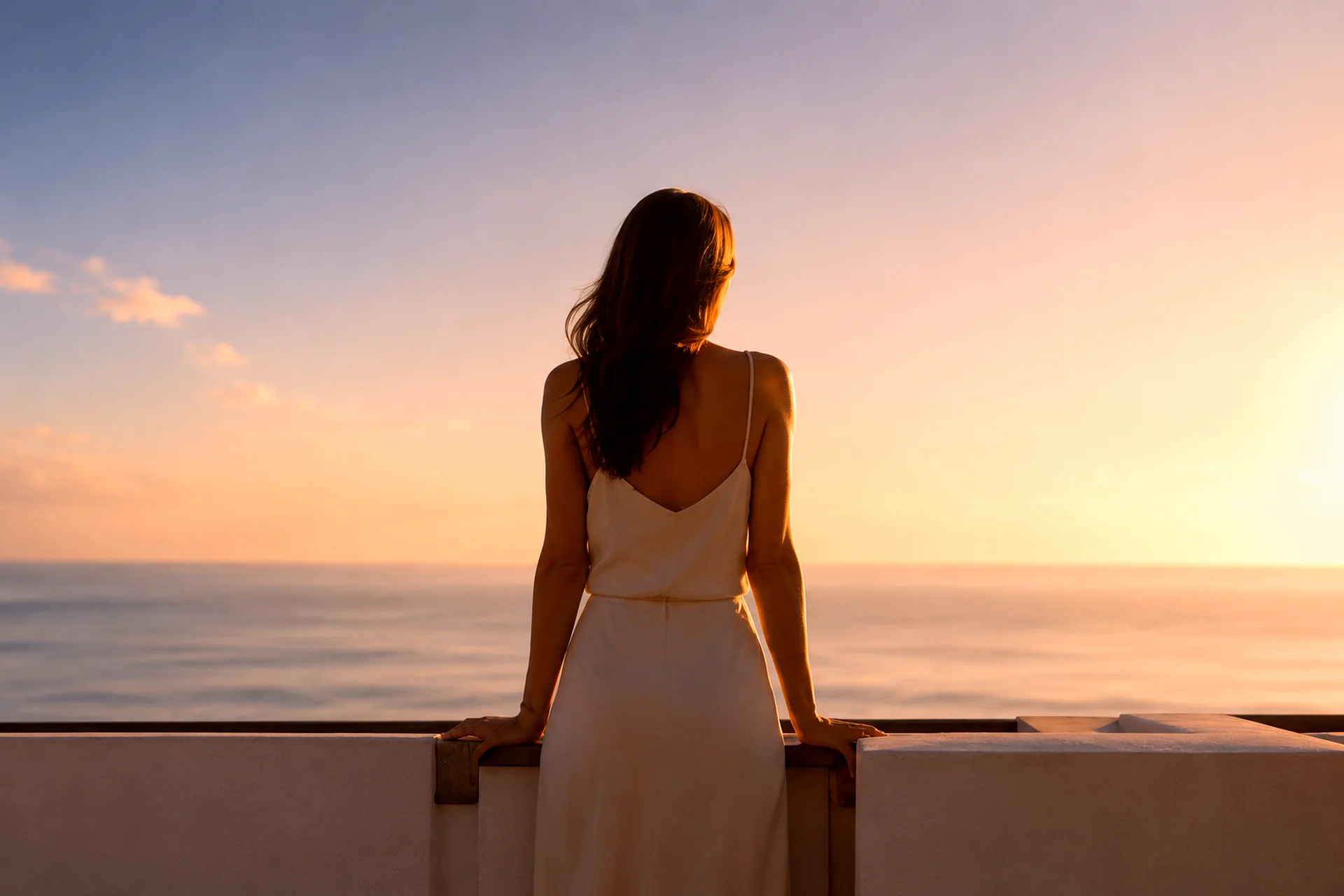 Frau blickt bei Sonnenuntergang über das Meer